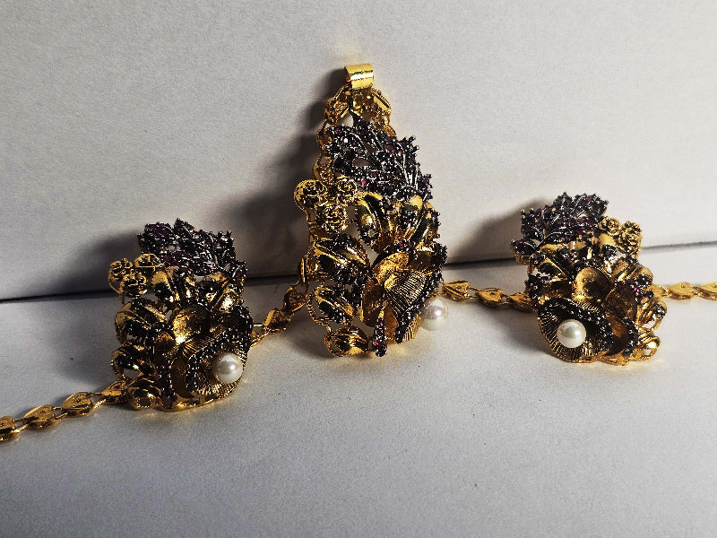 Gold and Black Floral Jewelry Set on a Gray Background